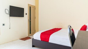 Ein Schlafzimmer mit einem Bett, einem an der Wand befestigten Fernseher und einer Tür.