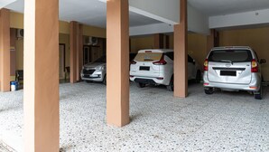 Überdachter Parkbereich mit drei Autos unter beigen Säulen.
