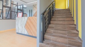 Un área de recepción de diseño moderno, una escalera con escalones de madera y una pared amarilla.