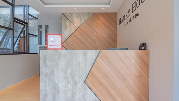 Un mostrador de recepción con diseño moderno, que combina paneles de hormigón y madera.