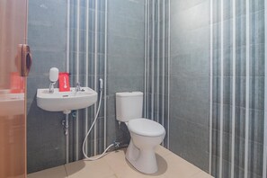 A bathroom with a white sink, a toilet, and a red bag on the wall.