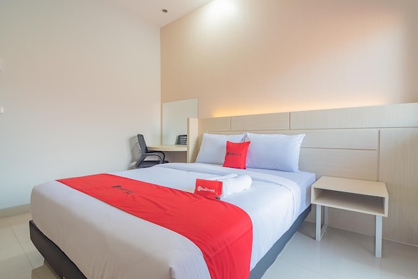 A hotel room with a neatly made bed, a bedside table, and a chair.