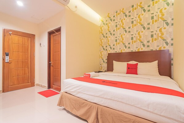 A hotel room with a bed, a wooden door, and a wall with a geometric pattern.
