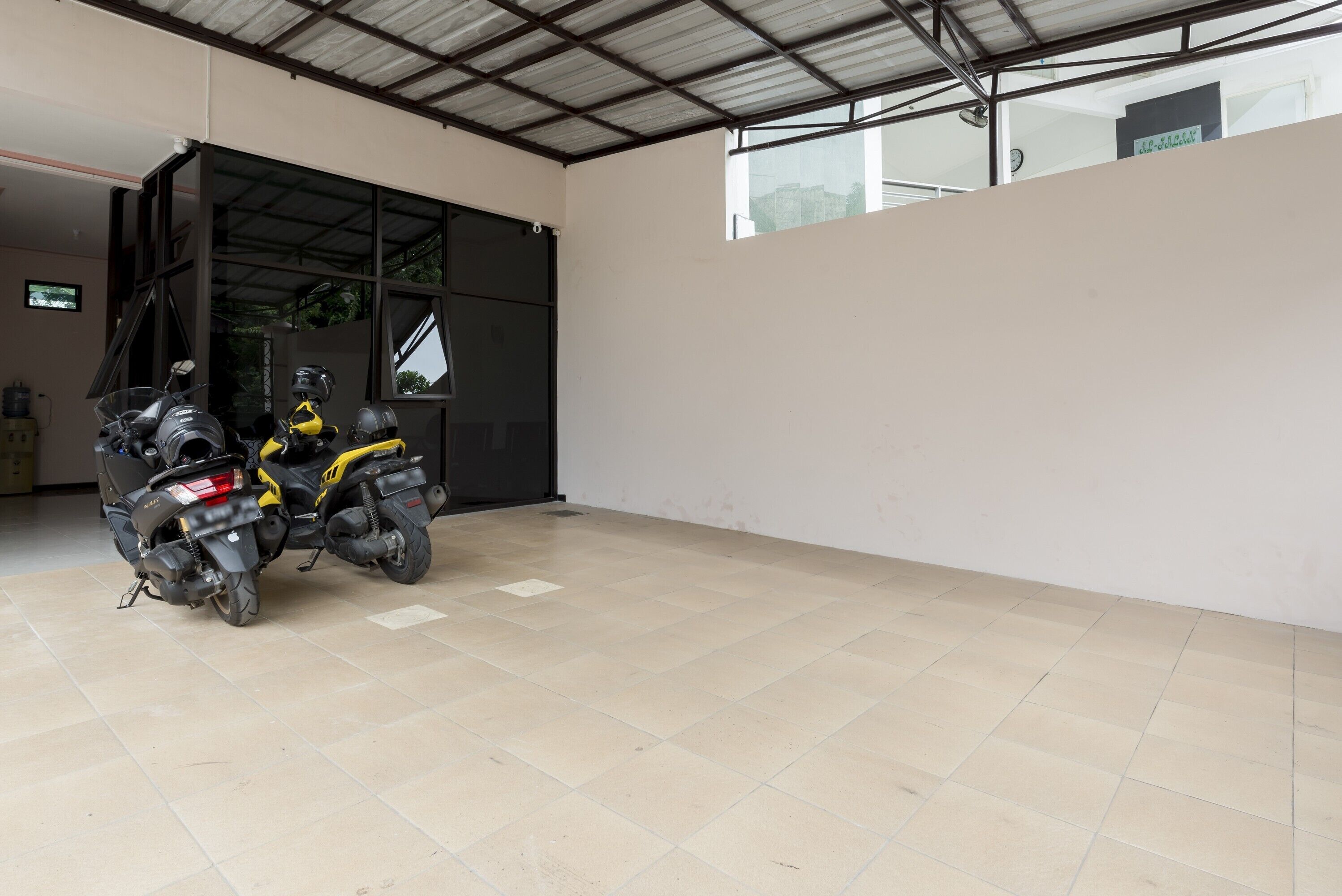 Un espacio interior amplio con suelo de baldosas y una gran puerta negra que da a otra habitación.