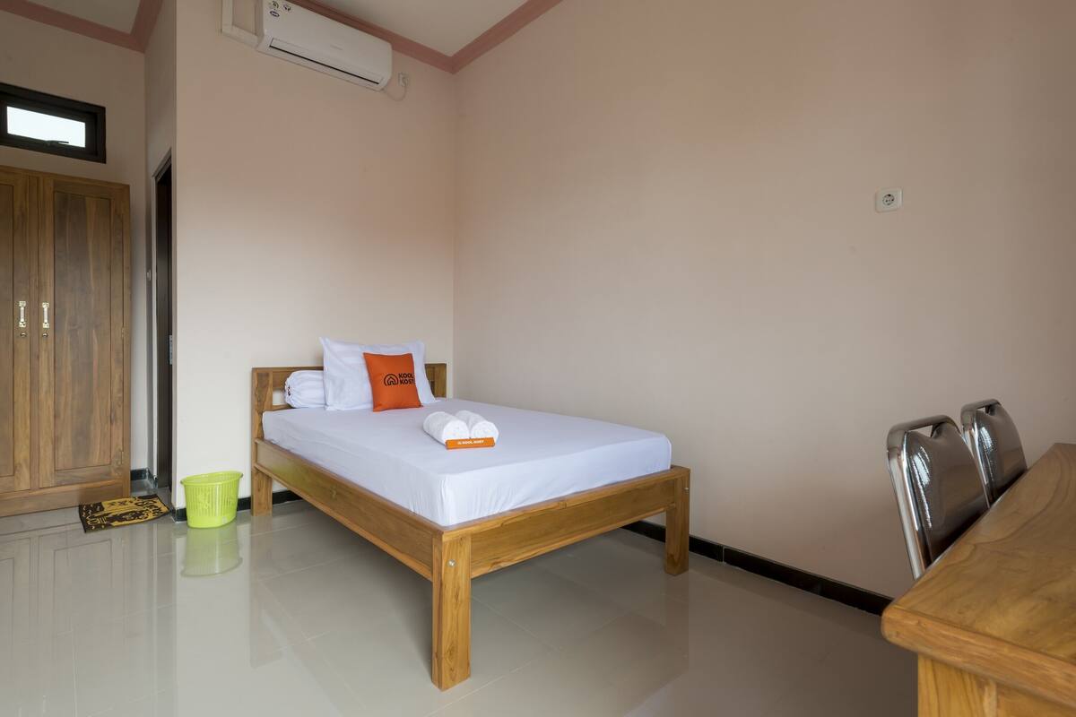 A bedroom with a wooden bed, a green basket, and a wooden wardrobe.