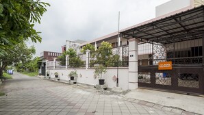 A gated residential area with a paved walkway, potted plants, and a sign for 'KOOL KOST'. - KoolKost Syariah near UPN Veteran (Surabaya)