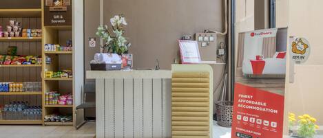 Un espace d’accueil d’hôtel avec un comptoir en bois, un rayon de cadeaux et de souvenirs, et une enseigne RedDoorz.