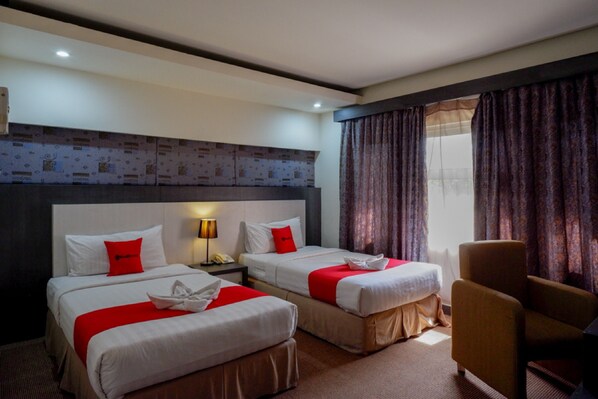 Een hotelkamer met twee bedden, een stoel en een nachtkastje met een lamp.