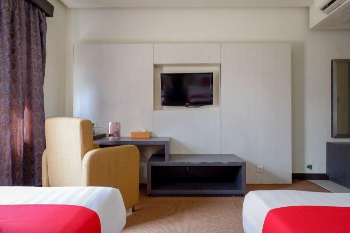 Habitación de hotel con dos camas, un escritorio, un televisor y un espejo grande.
