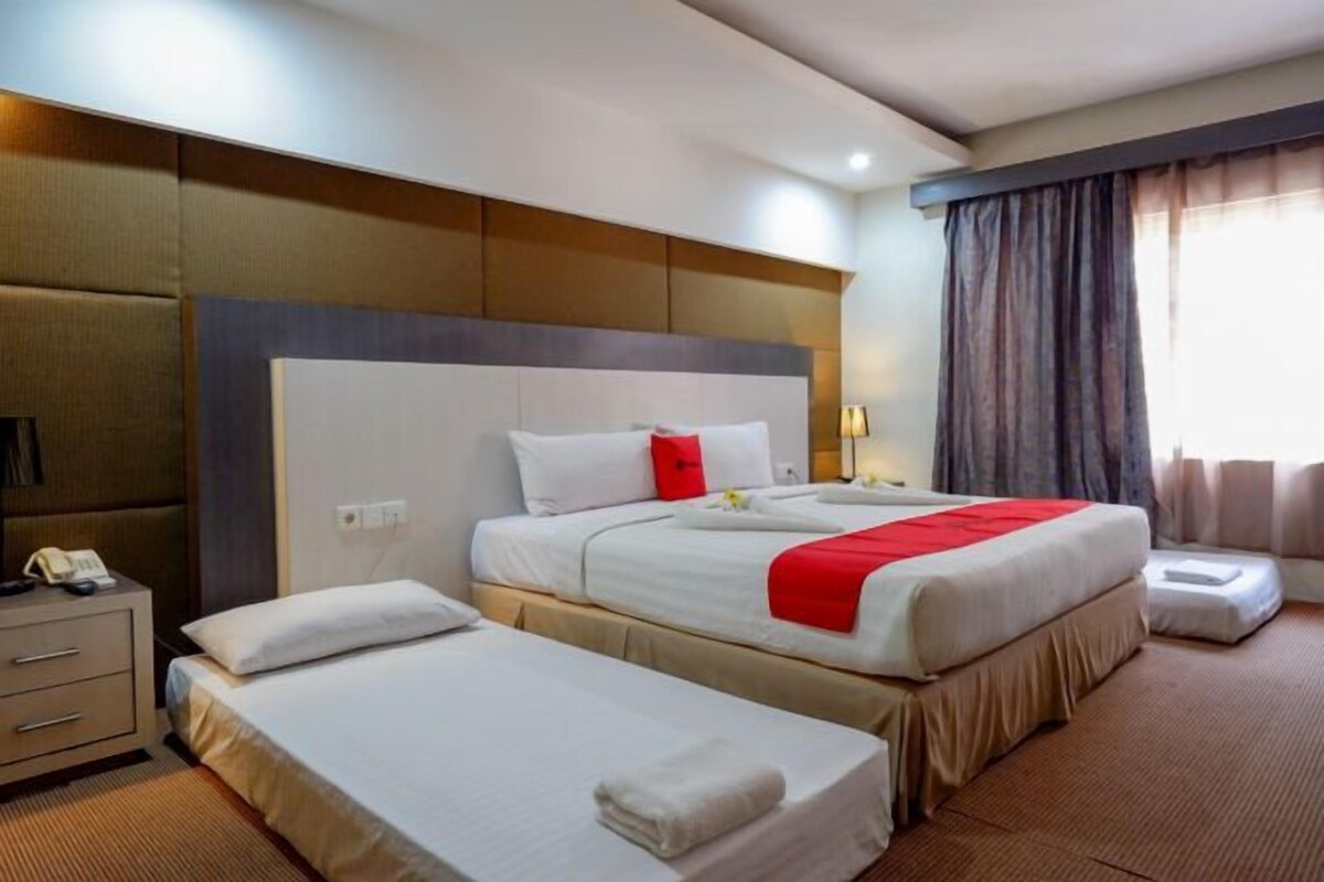 A hotel room with two beds, a bedside table with a phone, and a window with curtains.