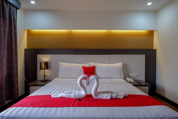 A hotel room with a bed, a red blanket, a pillow, a lamp, and a wall-mounted phone. - RedDoorz Plus near Hotel Benua Kendari (Kendari)