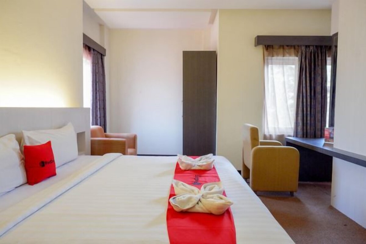 Habitación de hotel con una cama grande, un escritorio, una silla y vistas al exterior.