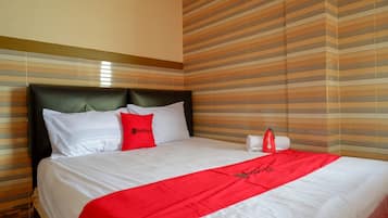 A hotel room with a large bed, striped wallpaper, and a red throw blanket.