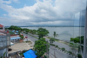A coastal cityscape with a view of the sea, a road, and buildings. - RedDoorz near Kendari Beach 2 (Kendari)