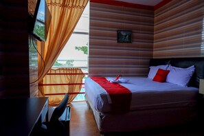 A hotel room with a bed, a TV, and a window with curtains. - RedDoorz near Kendari Beach 2 (Kendari)