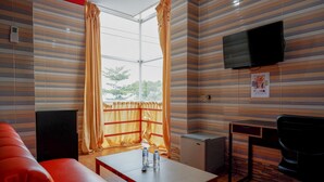 Una habitació d'hotel amb parets amb dibuixos de ratlles, un sofà vermell, una taula petita amb ampolles d'aigua i una televisió penjada a la paret, juntament amb un escriptori i una cadira.