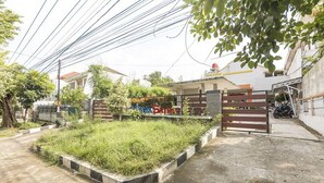 A residential area with a gated entrance, a paved driveway, and a grassy courtyard. - KoolKost Syariah @ Jalan Sisingamangaraja Semarang (Semarang)