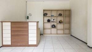 A hotel lobby with a reception desk and a shoe rack. - KoolKost Syariah @ Jalan Sisingamangaraja Semarang (Semarang)