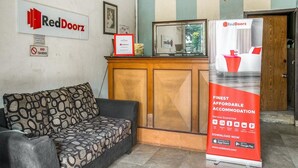 Un comptoir d’accueil RedDoorz avec un panneau, un certificat encadré et une banderole promotionnelle.
