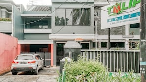 Un hôtel appelé « TILIP HOTEL », avec une enseigne, une voiture garée et une entrée fermée par un portail.