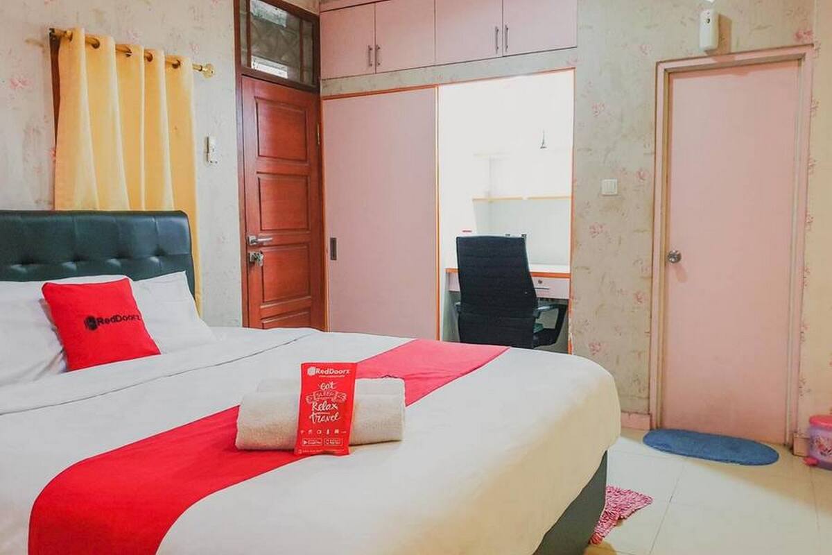 A hotel room with a bed, a desk, and a wardrobe.