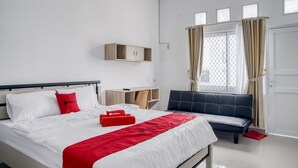 Une chambre d’hôtel avec un lit, une banquette, un bureau et une fenêtre avec des rideaux.