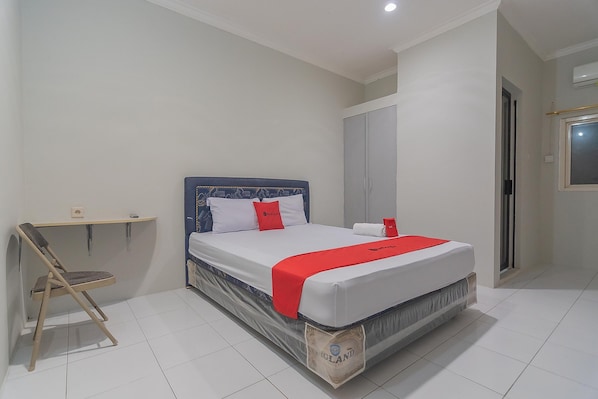 A bedroom with a bed, a chair, a wardrobe, and a window.