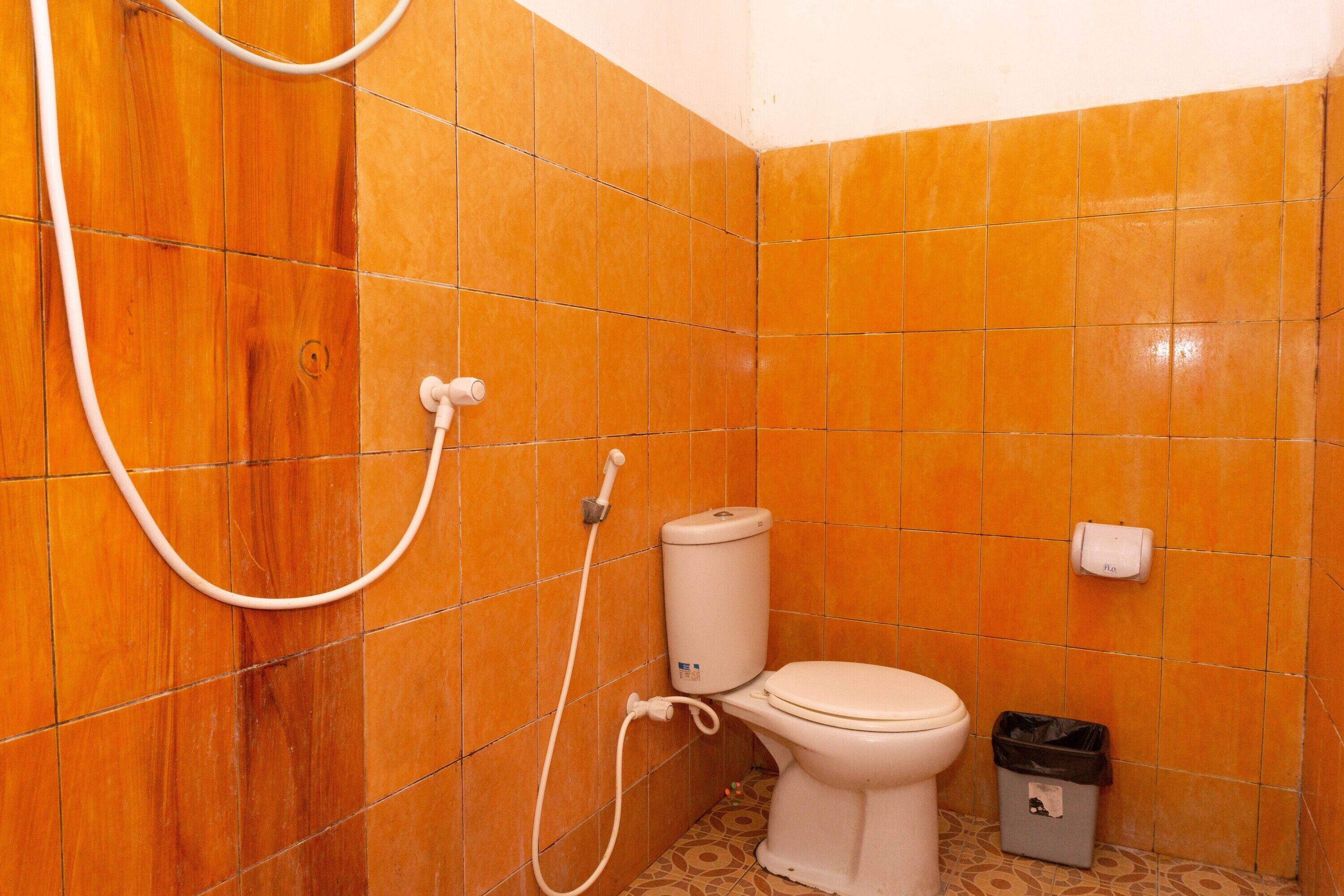 A bathroom with a toilet, a shower, and a trash bin.