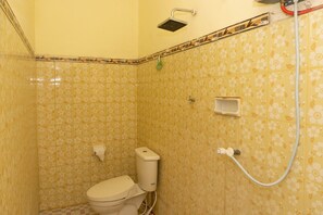 Une salle de bain équipée de toilettes, d’une douche et d’un porte-rouleau de papier toilette.