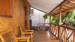A wooden deck with benches, a thatched roof, and a view of greenery.
