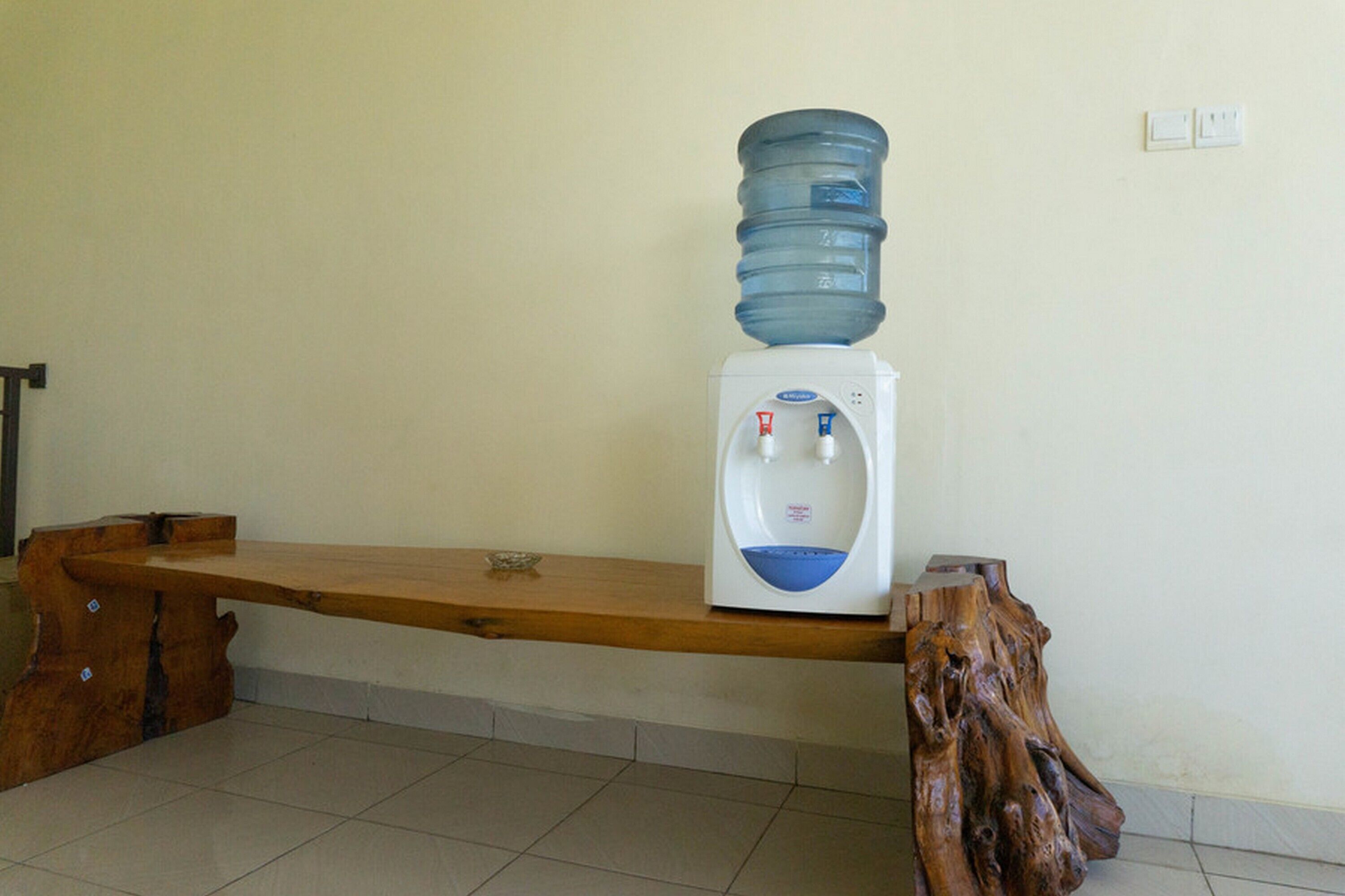 Un banco de madera con un dispensador de agua y una botella de agua grande encima.
