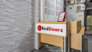A reception desk with a sign reading "RedDoorz" in a modern interior with tiled walls and air conditioning units. - RedDoorz @ Jemursari Surabaya 2 (Surabaya)