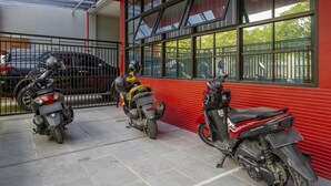 A parking area with three motorcycles and a car. - RedDoorz @ Jemursari Surabaya 2 (Surabaya)