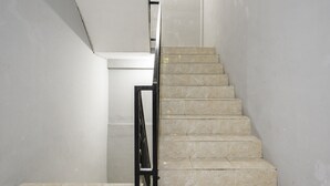 A staircase with beige tiles and a black metal railing. - RedDoorz @ Jemursari Surabaya 2 (Surabaya)