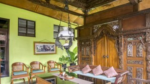 A traditional room with a green wall, wooden furniture, and a large ornate door. - RedDoorz Syariah @ Lempuyangan (Yogyakarta)