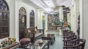 A spacious living area with a sofa, chairs, a coffee table, and a staircase. - RedDoorz Syariah @ Lempuyangan (Yogyakarta)