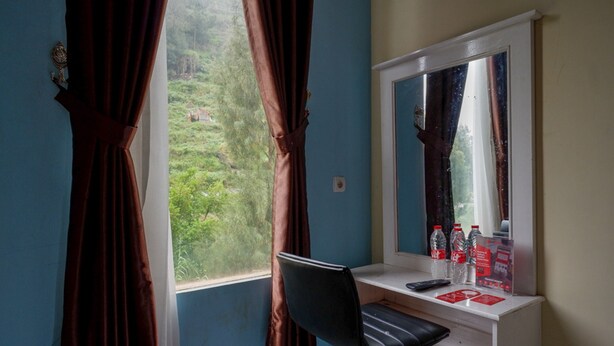 A room with a desk, a chair, a window with curtains, and a mirror. - RedDoorz @ Gerbang Dieng Plateau Area (Kejajar)