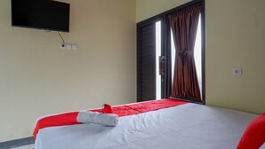 A hotel room with a bed, a TV mounted on the wall, and a window with curtains. - RedDoorz @ Gerbang Dieng Plateau Area (Kejajar)