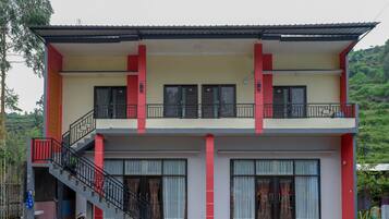 A two-story building with a balcony on the upper floor, a staircase leading to the ground floor, and large windows.