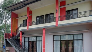 A two-story building with a balcony on the upper floor, large windows, and a staircase leading to the entrance. - RedDoorz @ Gerbang Dieng Plateau Area (Kejajar)