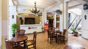 Zona de recepción con un letrero de RedDoorz, muebles de madera, un candelabro y una escalera al fondo.