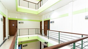 Interior con varios niveles, barandilla de madera, detalles verdes y puertas.