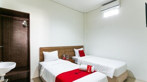 Habitación de hotel con dos camas, un armario de madera, un lavamanos y un aire acondicionado.