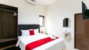Un dormitorio con cama, armario, mesita de noche, espejo y puerta.