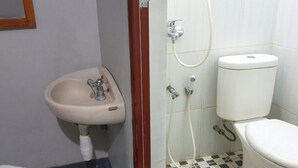 A bathroom with a pedestal sink, toilet, and shower. - RedDoorz @ Hotel Yaki Mamuju (Mamuju)