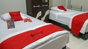 Two hotel beds with red and white bedding, a RedDoorz tag, and a brochure on the left bed. - RedDoorz @ Hotel Yaki Mamuju (Mamuju)