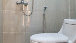 Un baño con inodoro, ducha y grifo empotrado.