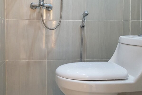 Un baño con inodoro, ducha y grifo empotrado.