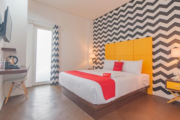 A modern hotel room with a large bed, a desk, and a chair. - RedDoorz Premium @ Hotel Hebat (Bandung)