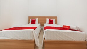 Two single beds with wooden frames and white bedding, each with a red pillow and a red blanket. - RedDoorz @ Graha Cemerlang Maros (Mandai)